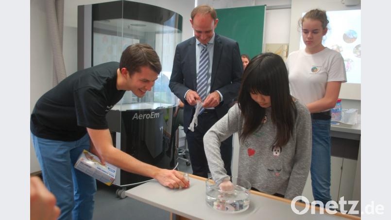 Zu Übungszwecken legten die Schülerinnen Antonia Kirchhoff (von rechts) und Nghi Pham künstliche Zähne in eine spezielle Flüssigkeit. Dr. Matthias Widbiller (von links) und Professor Torsten Reichert von der Uniklinik Regensburg gaben Tipps. Bild: Hanna Gibbs