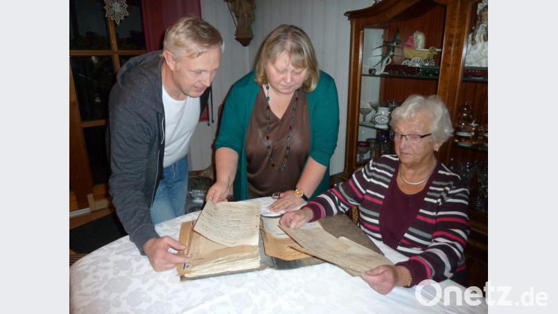 Emmi Schießl blättert mit Sohn Albert und Tochter Petra in alten Geschäftsunterlagen. Die handgeschriebenen Rechnungen von 1928 sind noch mit Reichsmark ausgegeben. Bild: Portner