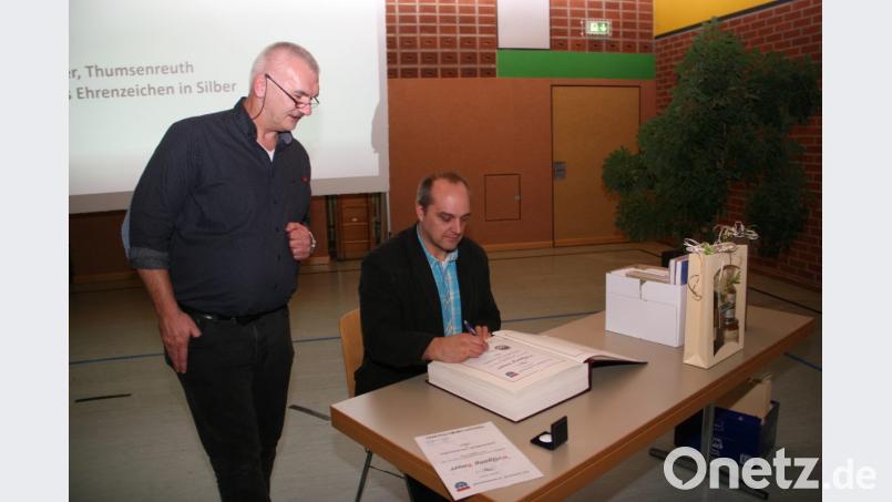 Nach seiner Auszeichnung darf sich Wolfgang Bauer ins Goldene Buch der Gemeinde Krummennaab eintragen. Zuvor wurde dem Thumsenreuther das gemeindliche Ehrenzeichen in Silber verliehen. Bild: wro