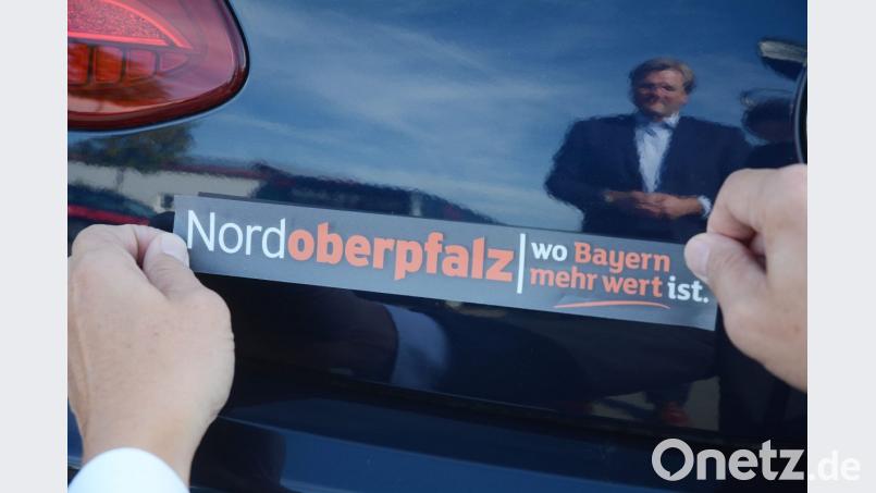 Wirtschaftsclub-Vorsitzender Anton Braun präsentiert ein Produkt der Marke Nordoberpfalz, einen Autoaufkleber: Nordoberpfalz - wo Bayern mehr wert ist. Bild: Gabi Schönberger