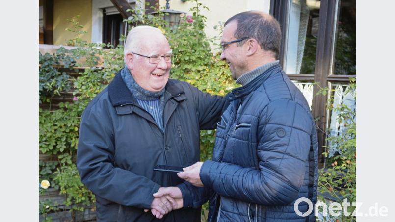 Mesner Siegfried Stock (rechts) übergibt Pfarrer Siegfried Wölfel das Handy von Peter Lehmeier. Bild: exb