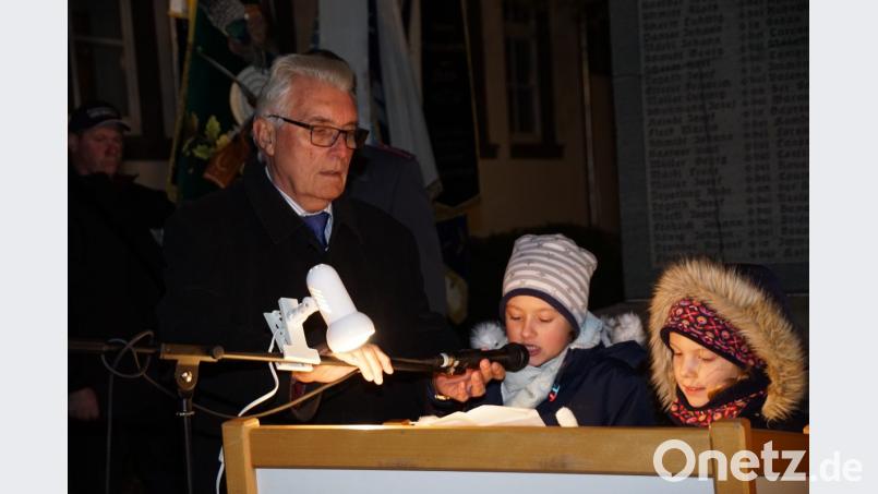 Zweiter Bürgermeister Josef Hecht hält das Mikrofon für Marie-Luise Schmid (Mitte) und Julia Stauter (rechts) bei ihrem Gedicht über den Volkstrauertag. Bild: bkr