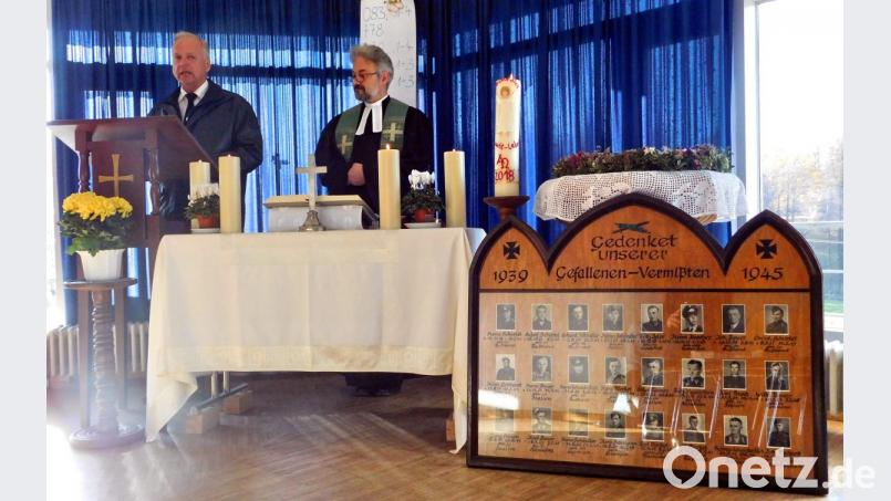 Gernot Hammon und Pfarrer Dirk Grafe (von links) sprechen bei der Gedenkfeier im Gemeindehaus aufrüttelnde Wort. Im Vordergrund steht die Ehrentafel für die 24 im Zweiten Weltkrieg gefallenen und vermissten Männer aus der Pfarrei. Bild: hai