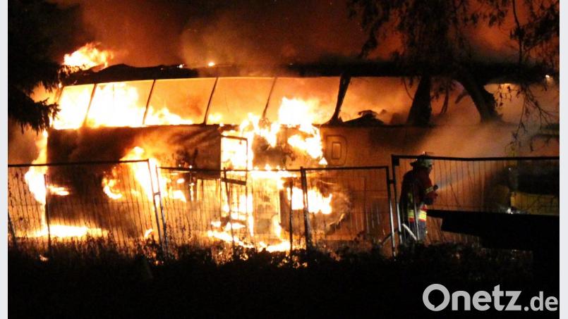 Ein Feuerwehrmann versucht brennende Reisebusse auf dem Gelände eines Busunternehmens bei Pottenstein (Kreis Bayreuth) zu löschen. Bild: Reporter 24/dpa