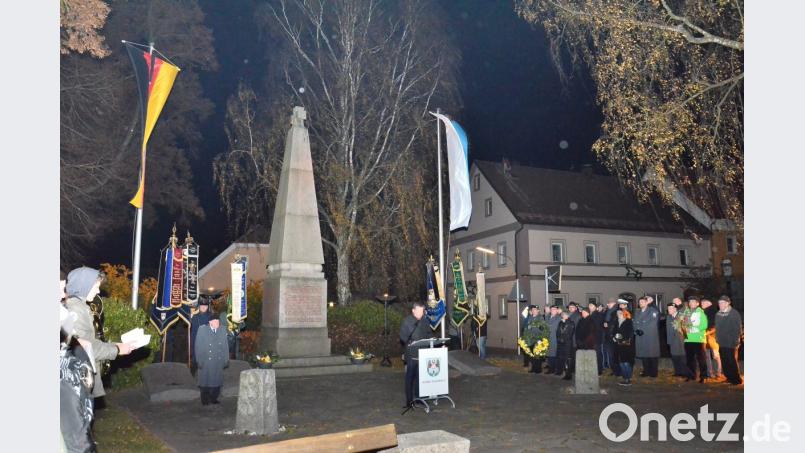 Bundestagsabgeordneter Uli Grötsch (Mitte) übernahm die Gedenkansprache zum Volkstrauertag vor dem nur spärlich erleuchteten Kriegermahnmal. Bild: fjo