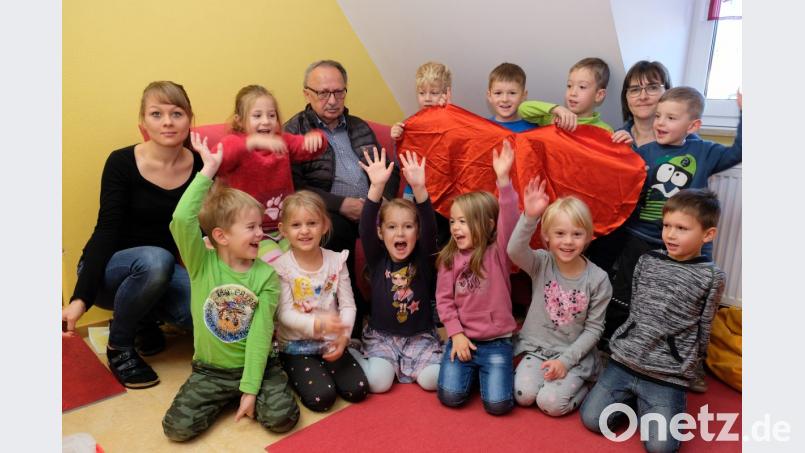 Gut gelaunte Kinder nehmen bei der Spendenübergabe Andreas Steinl senior, den stellvertretenden Vorsitzenden der Kinderkrebshilfe Oberpfalz-Nord, in ihre Mitte. Symbolisch zeigen die Buben und Mädchen ein rotes Herz für schwerkranke Kinder und ihre Familien. Vertreterinnen des Personals der Kindertagesstätte freuen sich mit. Bild: Dotzauer