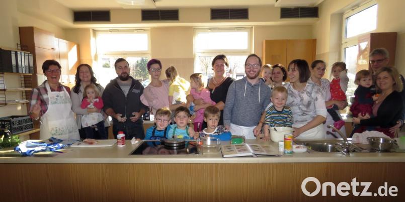 Die jungen Eltern und ihre Kinder haben viel Spaß beim Kochen mit Diätassistentin Barbara Michalski (li.), die ihnen auch die Ernährungspyramide für gesundes Essen erklärt. Bild: ubb