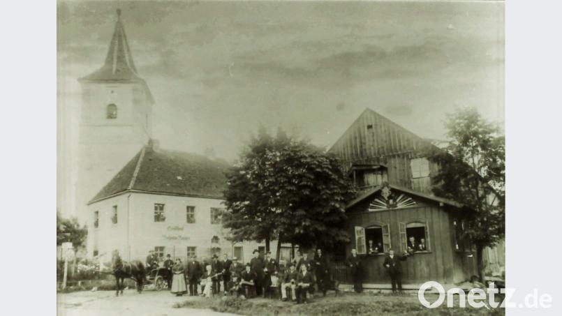 Die Leute auf dieser historischen Ansicht haben sich fein gemacht für den Fotografen. Die Tremmersdorfer posieren vor der Gastwirtschaft von Johann Burger im ehemaligen Schulhaus und seinem Saal mit Gartenhäuschen auf der gegenüberliegenden Straßenseite. Bild: hev