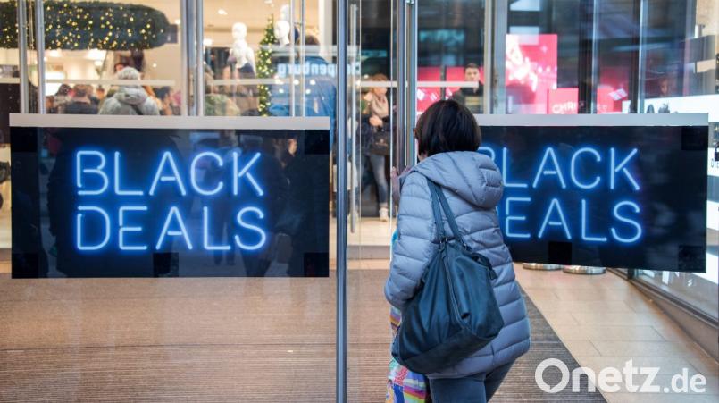 Eine Frau geht in ein Geschäft, an dessen Tür "Black Deals" steht. Am "Black Friday" locken viele Geschäfte mit großen Rabatten. Bild: Daniel Bockwoldt/dpa