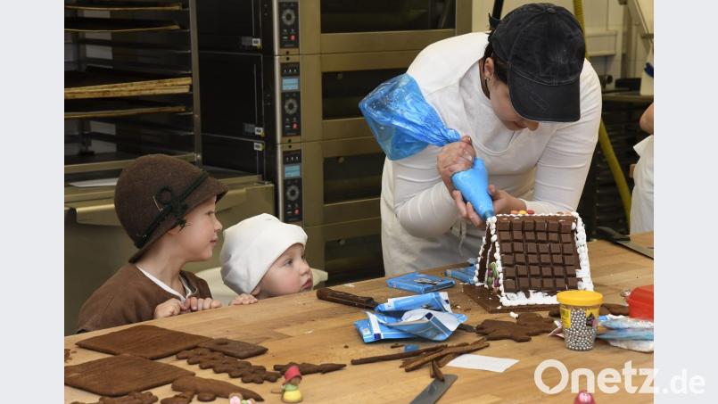 Bäckerlehrlinge dekorieren Knusperhäuschen zum Versteigern auf der Klösterlichen Weihnacht: Die Kinder Clemens und Greta schauen interessiert zu. Sie werden bei der Klösterlichen Weihnacht Hänsel und Gretel darstellen. Bild: Petra Hartl