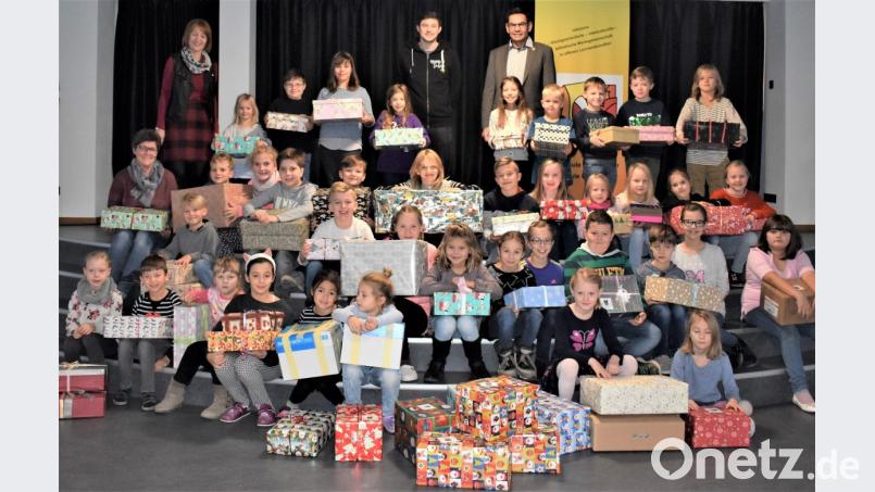 Philipp Koch vom Serviceclub &quot;Round Table&quot; (oben, Mitte) nimmt die Weihnachtspäckchen der Grundschulkinder entgegen. Mit auf dem Bild sind Rektor Thomas Schmidt (rechts daneben), Konrektorin Ruth Seitz (links oben) und Sabine Arnold (darunter). Bild: rgr