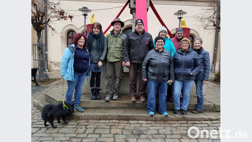 Viele fleißige Helfer versammeln sich zum Schmücken des Adventsbrunnens. Bild: stg