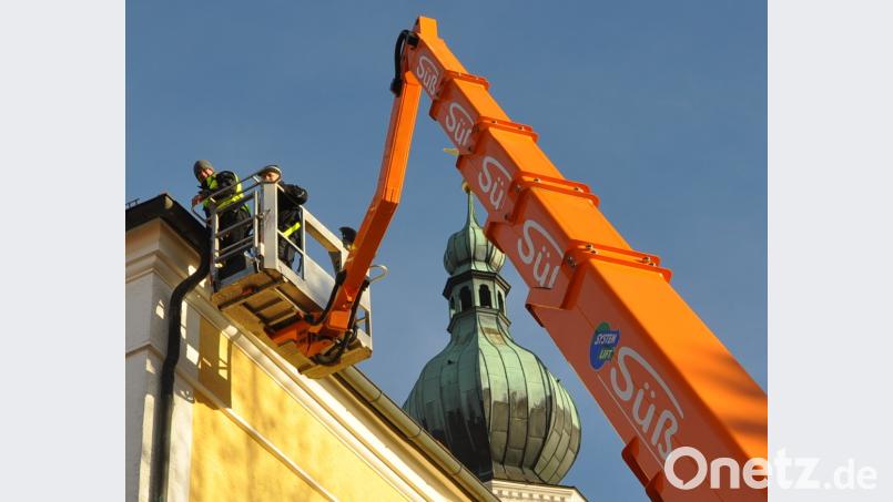 Regenwasser aus den Dachrinnen kann wieder durch die Abflussrohre abfließen. Hubert Schönberger (rechts) von der Kirchenverwaltung und Mitarbeiter Karl Huber (links) von der Firma Süß aus Nabburg reinigten am Donnerstagvormittag die verstopften Abflussrohre an der Pfarrkirche. Bild: es