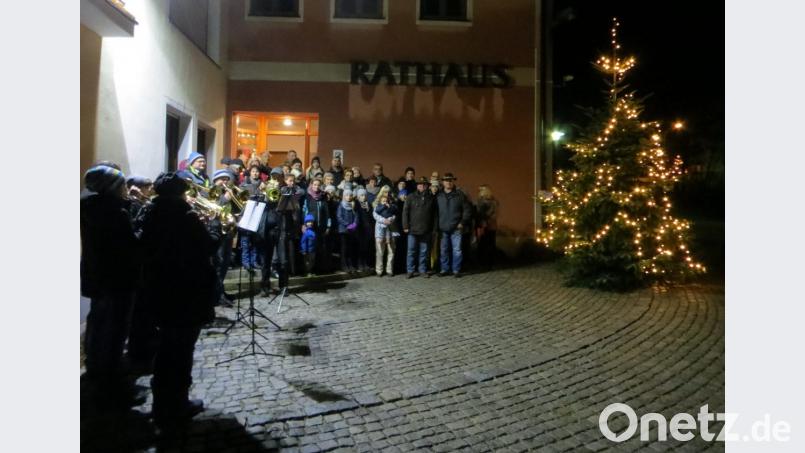 Traditionell eröffnen Siedlervorsitzender Hans Großer (Zweiter von rechts) und Bürgermeister Norbert Bücherl (links daneben, beide mit Hut) das erste Fenster des Lebenden Adventskalenders am Rathaus. Der evangelische Posaunenchor Thansüß (links vorne) begleitet die Veranstaltung musikalisch. Bild: nbu