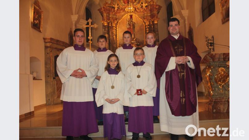 Kaplan Florian Frohnhöfer (rechts) nahm die beiden neuen Ministranten (vorne Mitte) Magdalena Brenner und Fabian Götz auf und ermunterte sie, die Ministrantenplaketten immer voller Stolz zu tragen. Bild: frd