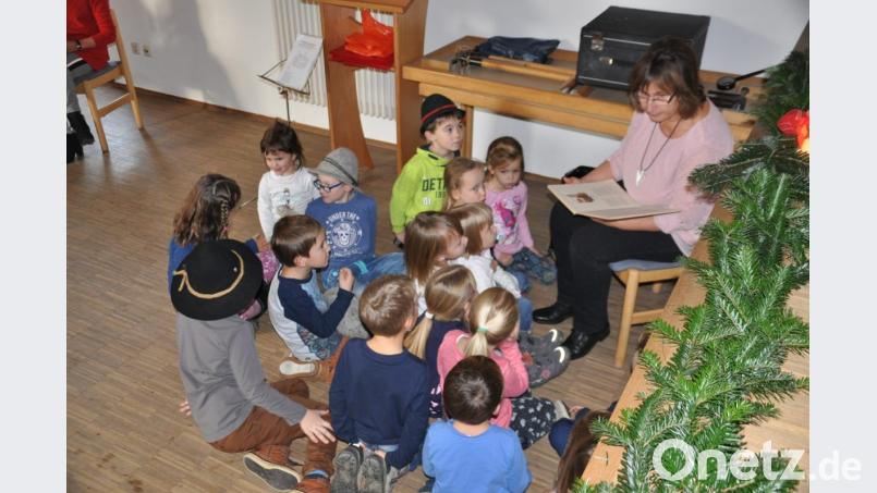 Brigitte Stich vom Seniorenkreis liest den Kindern nach ihrem Auftritt eine Weihnachtsgeschichte vor. Bild: ak