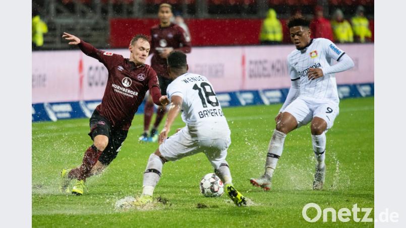 Wasserschlacht und natürlich Standprobleme: In dieser Szene kämpft der Nürnberger Federico Palacios (links) mit Leverkusens Wendell (Mitte) und Leon Bailey um den Ball. Bild: Nicolas Armer/dpa