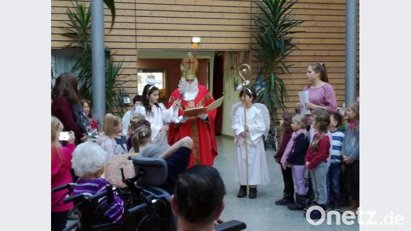 Der Nikolaus (Bruno Ponnath) mit seinen beiden Engeln und die Kita mit der Pinguin- und Elefantengruppe bereiteten den Senioren im Haus Falkenstein eine besinnliche Nikolausfeier. Bild: jzk