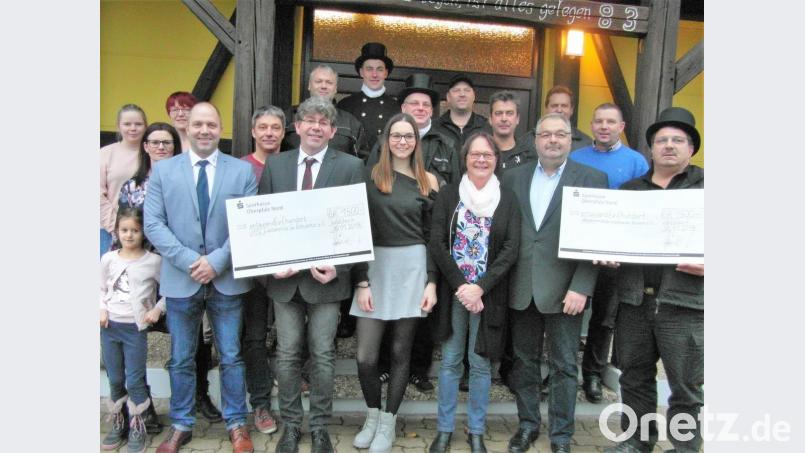 Im Kreise ihrer Mitarbeiter übergeben Bernhard und Martina Heindl (vorne, Zweiter und Dritte von rechts) jeweils einen 1500-Euro-Scheck an Manuel Müllner und Reinhard Kagerer (vorne von links) von den HPZ-Werkstätten sowie Bezirksschornsteinfegermeister Gerald Kastl (rechts). Bild: hl