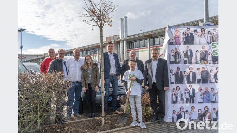 Zusammen mit einigen Vertretern der Firmengruppe Danhauser präsentiert Jonas Reißenweber von "Plant fot the Planet" einen frisch gepflanzten Baum auf einem Baumarktparkplatz. Bild: exb