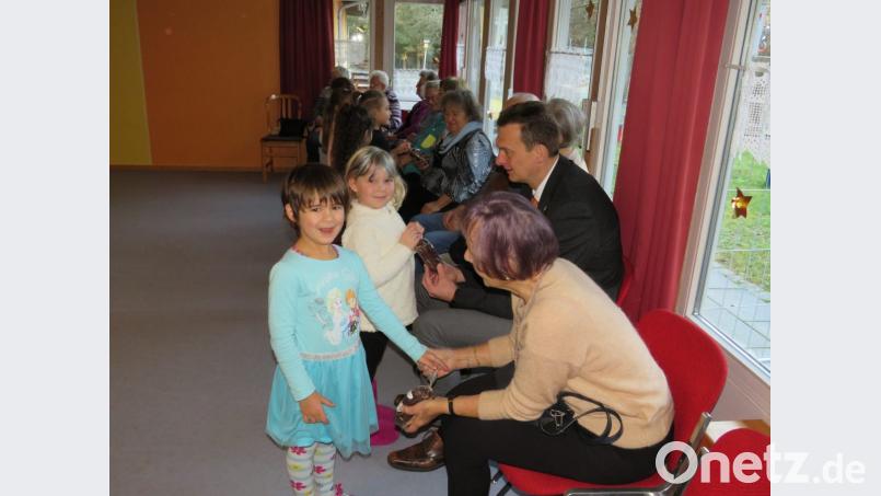 Mit einem kleinen Stollen beschenken die Kinder die Senioren des AWO-Seniorenclubs. Bild: adj