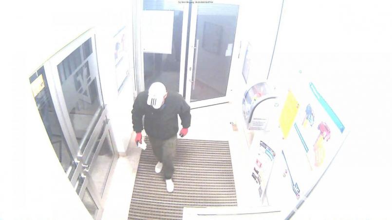 Der Täter betritt die Bank. Auf diesem Bild sind seine Kleidung und seine weiße Mütze gut zu sehen. Bild: Polizei Amberg