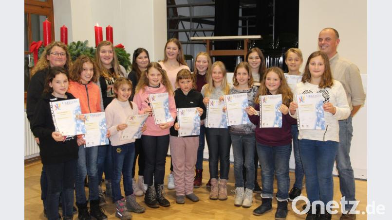 Zusammen mit den Kindern der Bläserklasse16 und den frisch gekürten &quot;Silberlingen&quot; des Nachwuchsorchester freuen sich Bläserklassenleiterin Karin Raab (links) und musikalischer Leiter Markus Ferstl (rechts) über die guten Ergebnisse ihrer Schützlinge bei den Leistungsprüfungen. Bild: bph