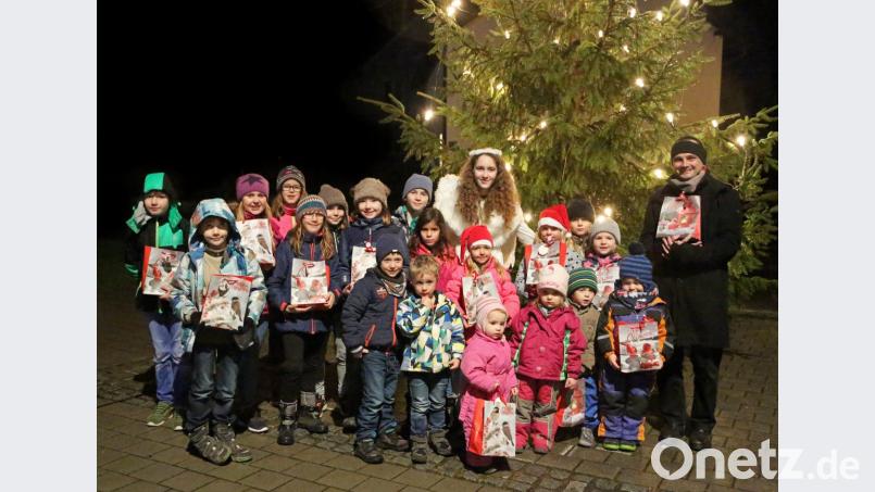 Beim Glühweinabend am Dorf-Christbaum begrüßt Pfarrer Hartmut Klausfelder (rechts) das Christkind (Ines Preißinger, Mitte). Dieses hat viele Geschenke für die Kinder des Dorfes dabei. Bild: ow
