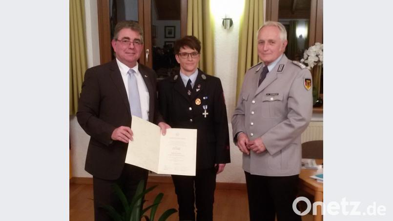 Auf Antrag von Bürgermeister Norbert Bücherl (links) händigt Bezirksvorstandsmitglied Theophil Schindler (rechts) vom Volksbund Deutsche Kriegsgräberfürsorge die Verdienstspange in Bronze mit Urkunde an Isolde Schmidt von der Feuerwehr Seugast aus. Bild: Gerhard Lindthaler