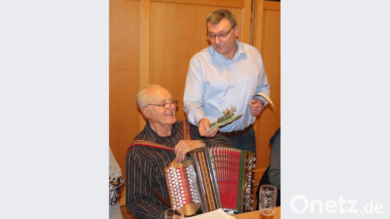 Rudolf Fink stimmt mit seinem Instrument auf Weihnachten ein und begleitet den Gesang der Gäste. Josef Häckl bedankt sich dafür mit einem kulinarischen Geschenk. Bild: rpp