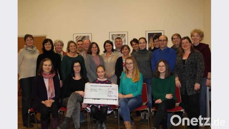 .Anna-Lena (vorne, Mitte), jüngstes Mitglied des Familienchors Klangfarben, übergibt im Beisein von Chorleiterin Kataryna Menges (vorne, links) und den anderen Ensemblemitgliedern eine Spende über 600 Euro. Das Geld stammt aus dem Konzerterlös. Denise Frech (vorne, Zweite von rechts), Vorsitzende des Fördervereins Ninos Freunde, nimmt mit Stellvertreterin Jennifer Jobst (vorne, Zweite von links), den Scheck entgegen. Bild: ads