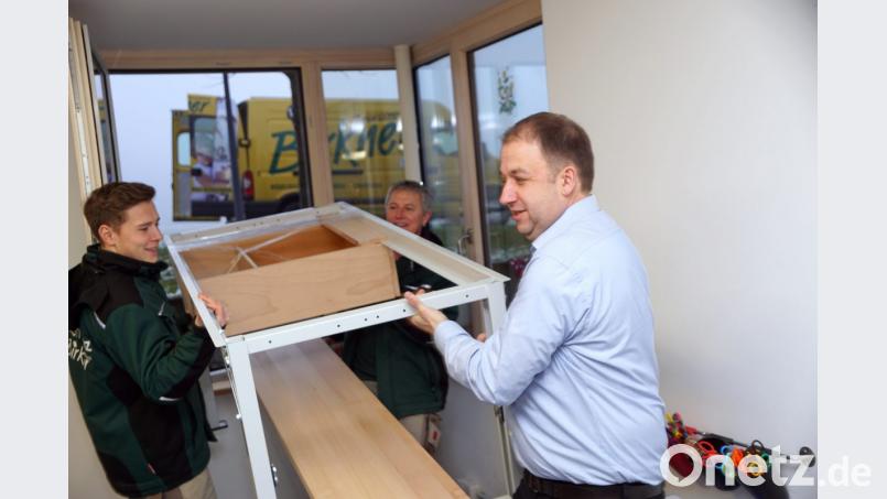 Mit vereinten Kräften heben Julian und Josef Birkner sowie SOS-Kinderdorfleiter Holger Hassel (von links) die Werkbank durch ein Fenster in den Werkraum. Bild: bkr