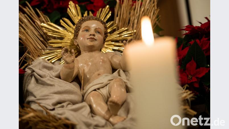 In einer Krippe liegt eine Holzfigur von Jesus. Daneben brennt eine Kerze. Bild: Sven Hoppe/dpa