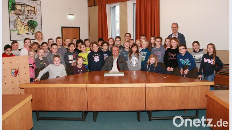 Die Buben und Mädchen der 4. Grundschulklassen hatten für Bürgermeister Dutz einen dicken Fragenkatalog mitgebracht. Begleitet wurden sie von Konrektor Stefan Mühlbauer (rechts) und Lehrerin Gabi Vollath (links). Bild: wro