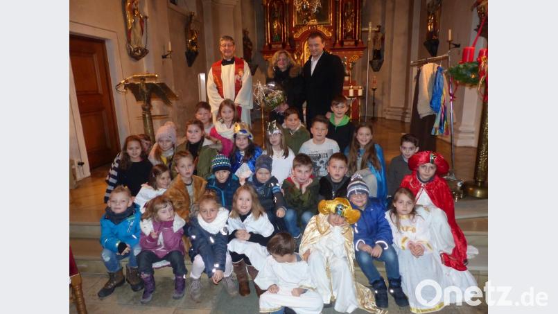 Bürgermeister Anton Kappl überreicht zum Dank an Margit Walter Präsente im Beisein von Pfarrer Adam Nieciecki (hinten von rechts) und die Kinder brachten ihren Dank gesanglich zu Gehör. Bild: sl