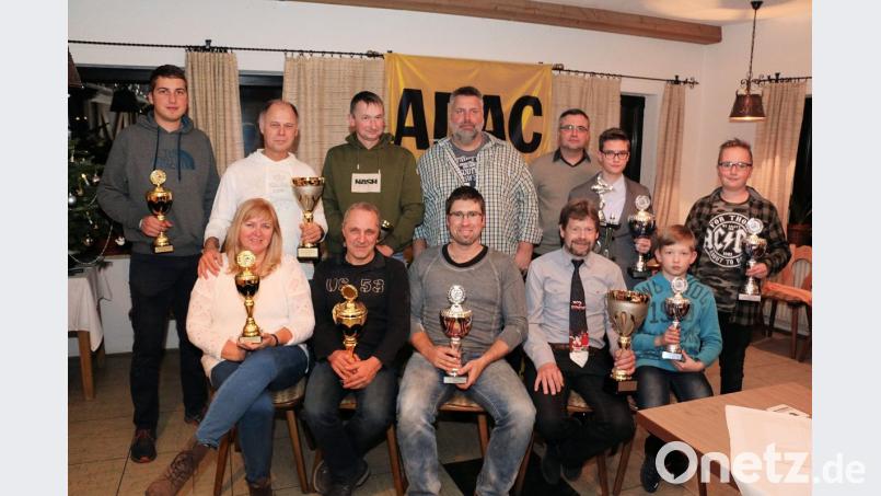 Vorsitzender Stefan Schmalzreich (hinten, Mitte) würdigt bei der Jahresabschlussfeier die sportlichen Leistungen der AC-Mitglieder, vor allem aber das Engagement bei den Arbeitseinsätzen. Die Motorsportler freuen sich über Pokale und Trophäen. Bild: bsc