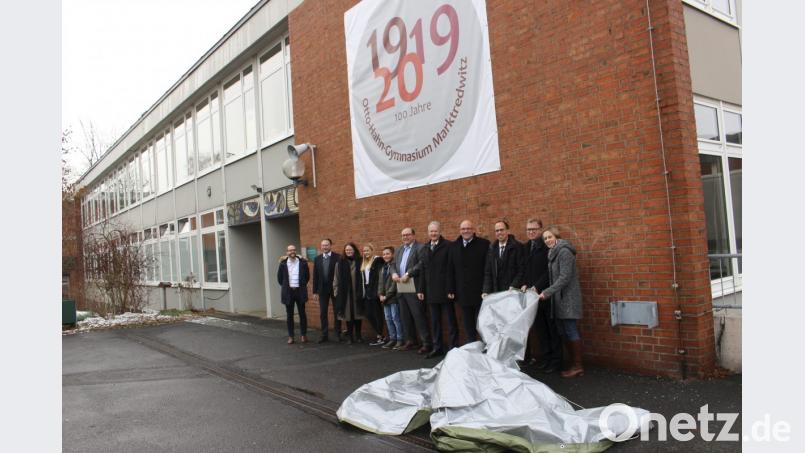 Vertreter der Schule und der Politik enthüllten am Eingang des Marktredwitzer Gymnasiums das Banner, das auf 100 Jahre OHG hinweist. Bild: fphs