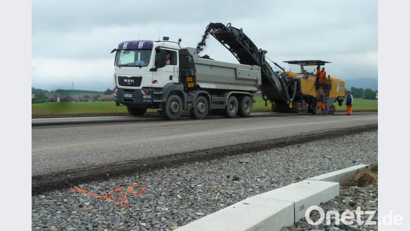 2,20 Meter an Breite schafft die Asphaltfräse. Sie muss die Straße deshalb viermal entlangfahren. Am Freitagmittag war die Kolonne bei der Kreuzung Nunzenried-Johannisberg unterwegs. Die Bankette für die barrierefreien Bushaltestellen (im Vordergrund) sind bereits gesestzt. Auch die Sanierung der Brücken aus der Vorkriegszeit ist abgeschlossen. Bild: ptr