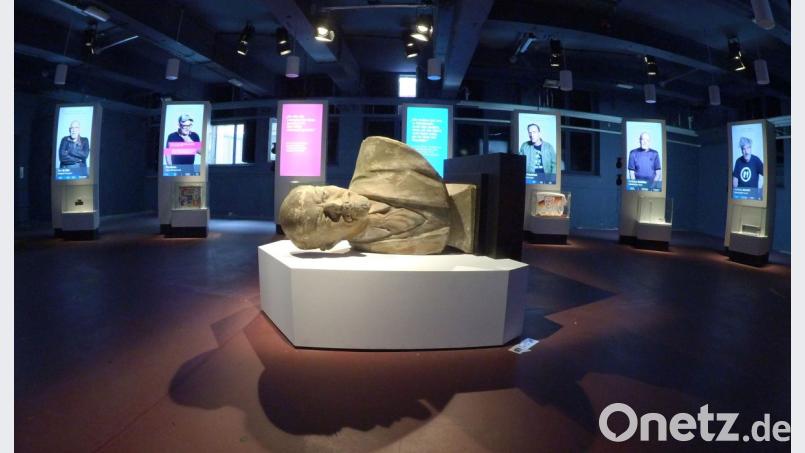 Eine umgestürzte Lenin-Büste liegt in der Alte Münze vor multimedialen Stelen. Dort berichten Prominente über ihre Erfahrungen im ehemals geteilten Berlin. Bild: Paul Zinken/dpa