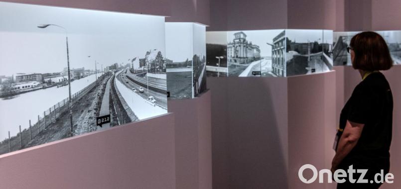 Eine Frau steht in der Alte Münze vor historischen Fotos aus dem ehemals geteilten Berlin. Die Bilder sind Bestandteil der Multimedia-Ausstellung "Nineties Berlin". Bild: Paul Zinken/dpa