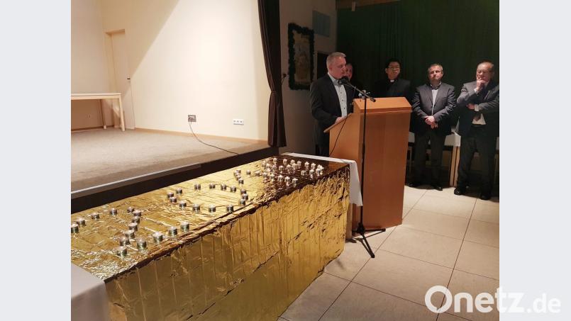 Am Rednerpult Bürgermeister Jürgen Kürzinger, daneben Pater Samuel Patton, der neue Kirchenpfleger Georg Schraml und sein Vorgänger Franz Eller. Bild: hzi