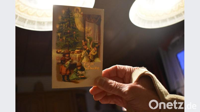 Auf dieser Karte erscheint erst im Schein des Lichtes das Christkind, welches die Gaben unter den Weihnachtsbaum legt. Die Kinder spielen mit ihren Geschenken. Mädchen haben Puppen und Holzspielzeug, die Jungen stellen mit Schwert, Pickelhaube und Pferd den Krieg nach. Bild: lue