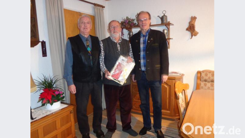 Helmut Ruhland (links) und Norbert Dineiger gratulieren Jubilar Dieter Schunck (Mitte) mit einem Buch über die „Geschichte der Eisenbahn“. Bild: exb