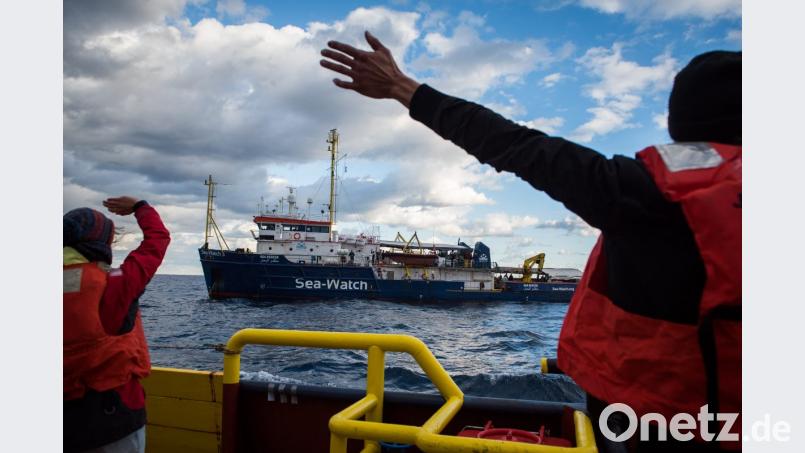Dieses von Sea-Watch.org zur Verfügung gestellte Foto zeigt gerettete Migranten und neue Besatzungsmitglieder an Bord der Sea-Watch 3. Im Vordergrund verabschieden sich Besatzungsmitglieder der Mission 17 beim Besatzungswechsel. Bild: Chris Grodotzki/Sea-Watch.org/dpa