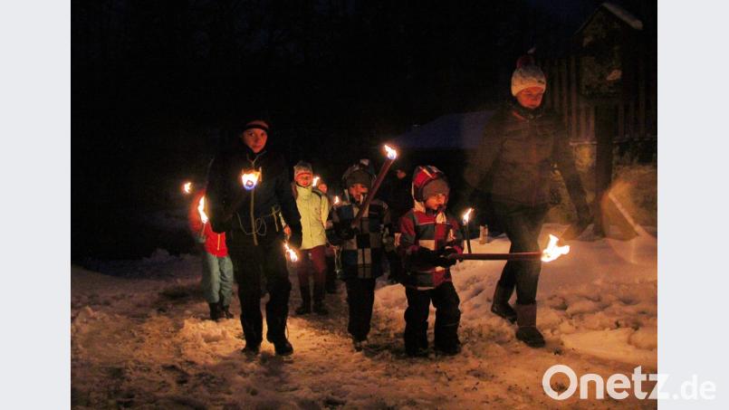 Mit Fackeln machen sich die Outdoor-Kids des Fichtelgebirgsvereins und weitere Kinder daran, das Winterfeuer zu entzünden. Bild: hai
