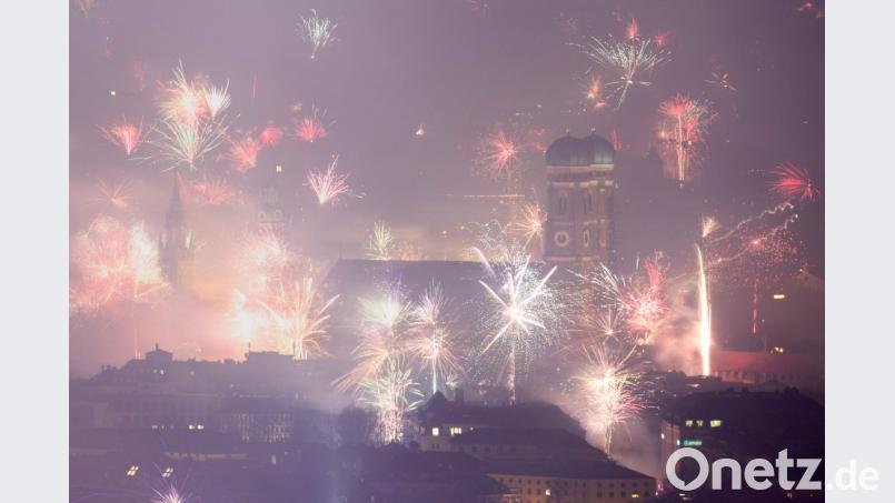 Feuerwerksraketen explodieren in der Silvesternacht über der Frauenkirche in München. Aber auch Rauchschwaden ziehen über die Stadt hinweg. Bild: Matthias Balk/dpa