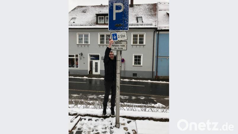 Bürgermeister Hermann Ach montiert selbst die jahrzehntelange Verkehrsregelung am Marktplatz mit Parkscheibe und einer Parkzeitbeschränkung auf zwei Stunden ab. Bild: gi