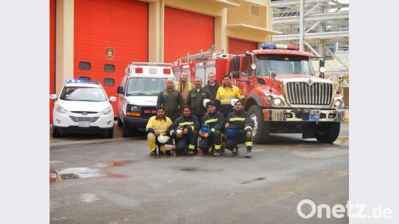 Roman Schenk (hinten, links) und seine Truppe stellen sich vor dem Feuerwehrauto zum Gruppenfoto auf. Bild: exb