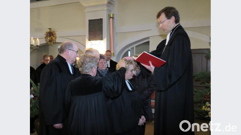 Dekan Dr. Wenrich Slenczka (rechts) segnet Pfarrerin Nadine Schneider. Ausgewählte Kirchenvorstände sprechen Segenssprüche. Bild: ubb