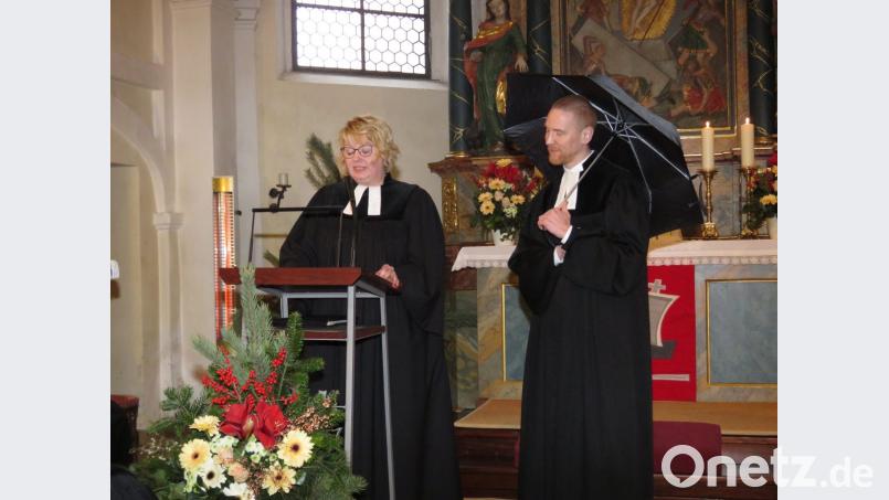 Unterm Schirm gut beschützt wünscht sich Pfarrer Christoph Zeh die Gemeinschaft in den Kirchengemeinden und die Zusammenarbeit mit seiner Kollegin Nadine Schneider. Das demonstriert er zur Erheiterung der Gäste mit einem ganz normalen Regenschirm. Bild: ubb